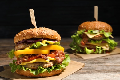 Photo of Tasty burgers with bacon on table. Space for text