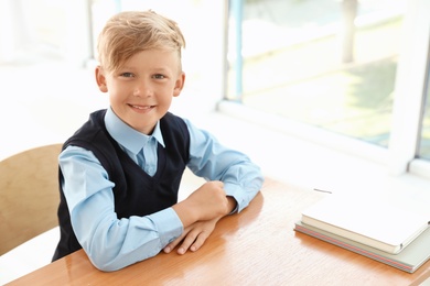 Little boy in stylish school uniform at desk