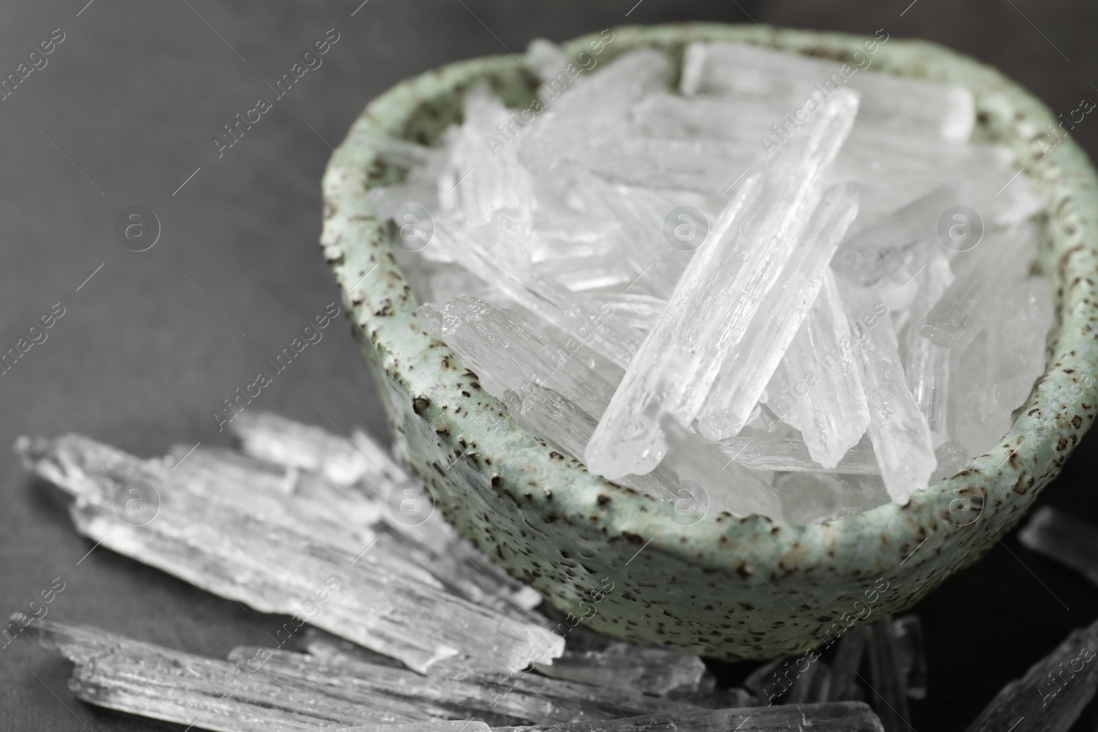 Photo of Menthol crystals in bowl on grey background, closeup