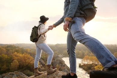 Couple of hikers with backpacks climbing up mountains