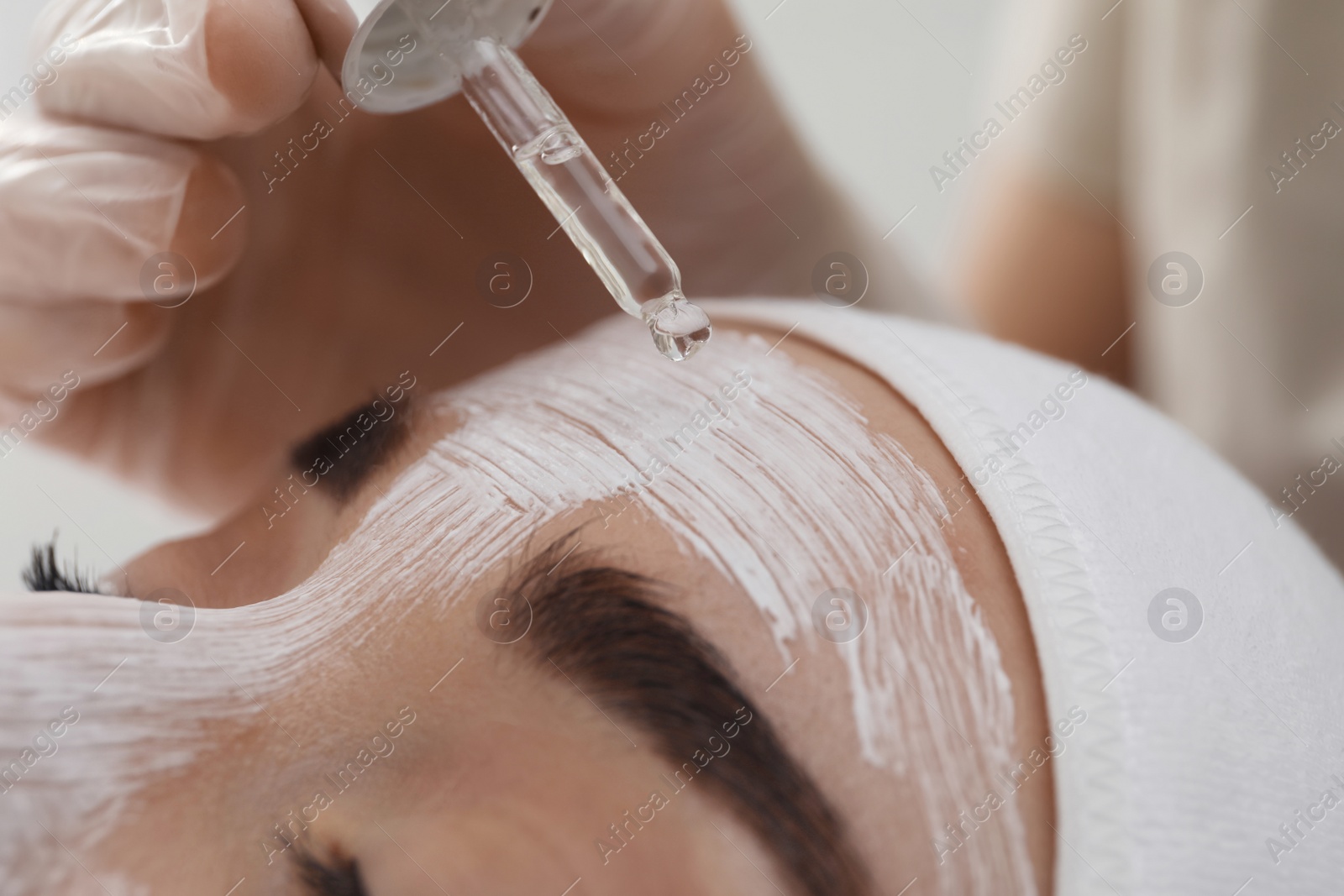 Photo of Young woman during face peeling procedure in salon, closeup