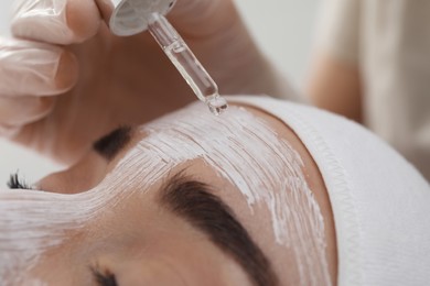 Photo of Young woman during face peeling procedure in salon, closeup