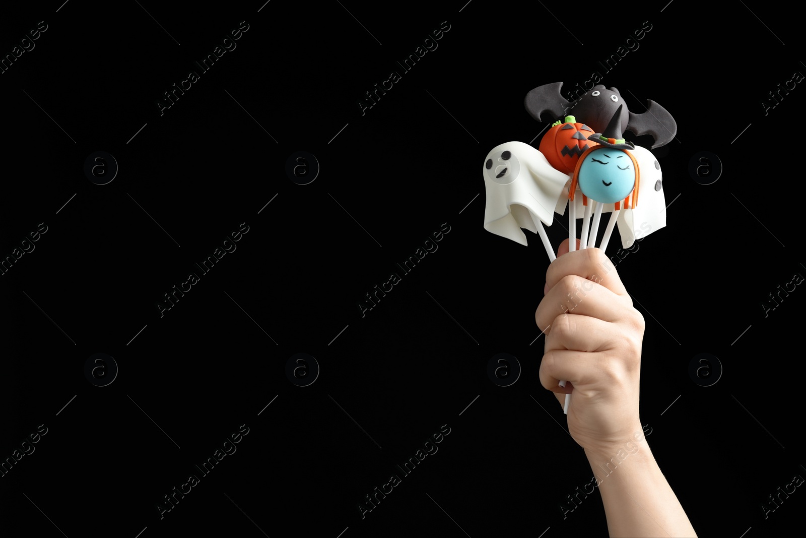 Photo of Woman with delicious cake pops and space for text on black background, closeup. Halloween celebration