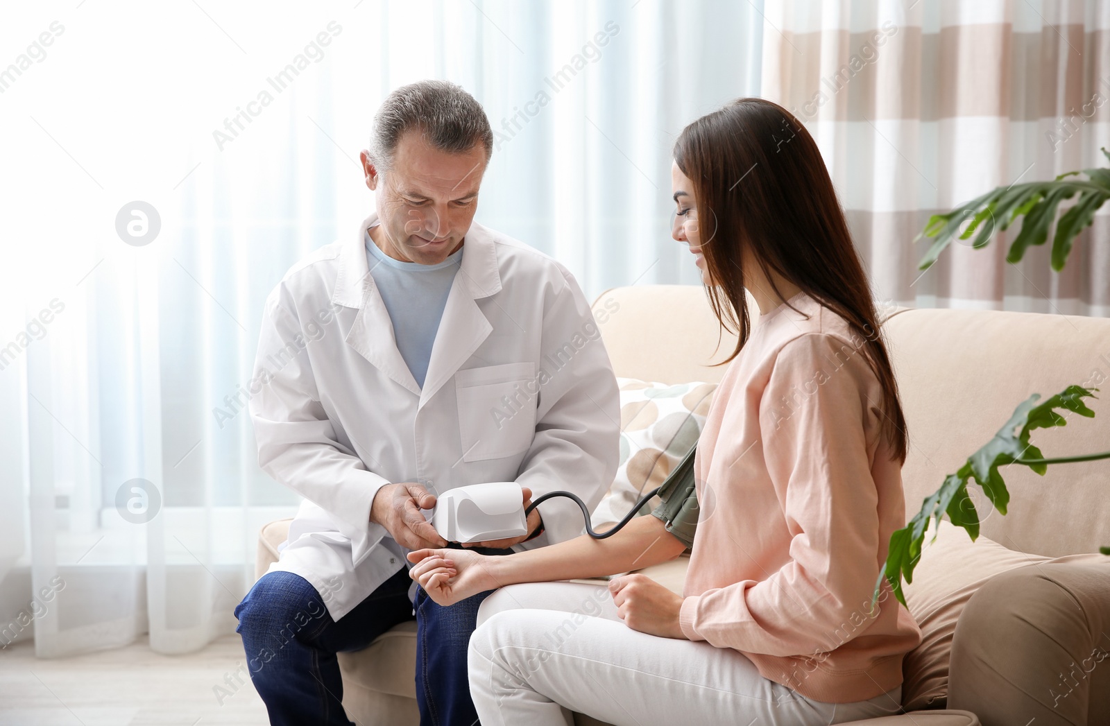 Photo of Doctor checking young woman's pulse with medical device at home