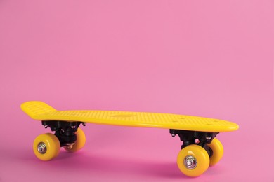 Photo of Yellow skateboard on pink background. Space for text