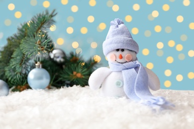Photo of Snowman toy on snow against blurred festive lights. Christmas decoration