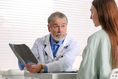 Photo of Orthopedist showing X-ray picture to patient in clinic