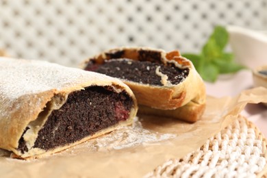 Photo of Delicious strudel with poppy seeds and cherries on mat, closeup