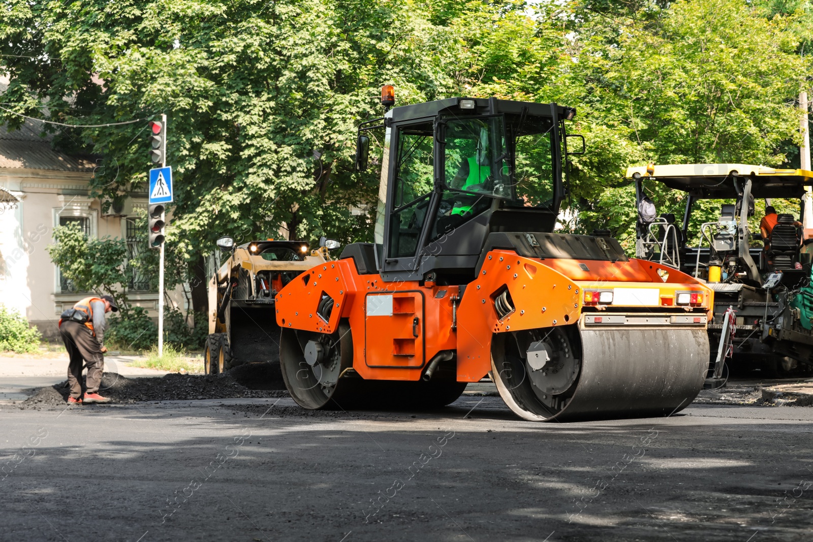 Photo of MYKOLAIV, UKRAINE - AUGUST 05, 2021: Workers laying new asphalt with heavy machinery on city street. Road repair service