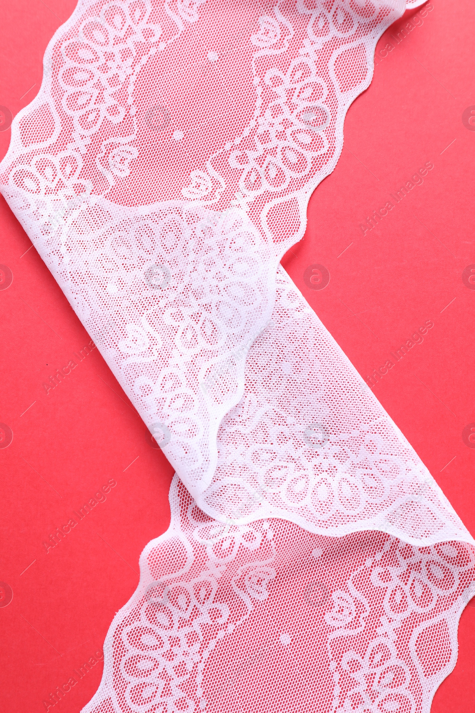 Photo of White lace on red background, top view