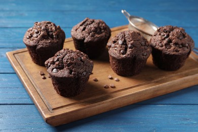 Photo of Delicious chocolate muffins on blue wooden table