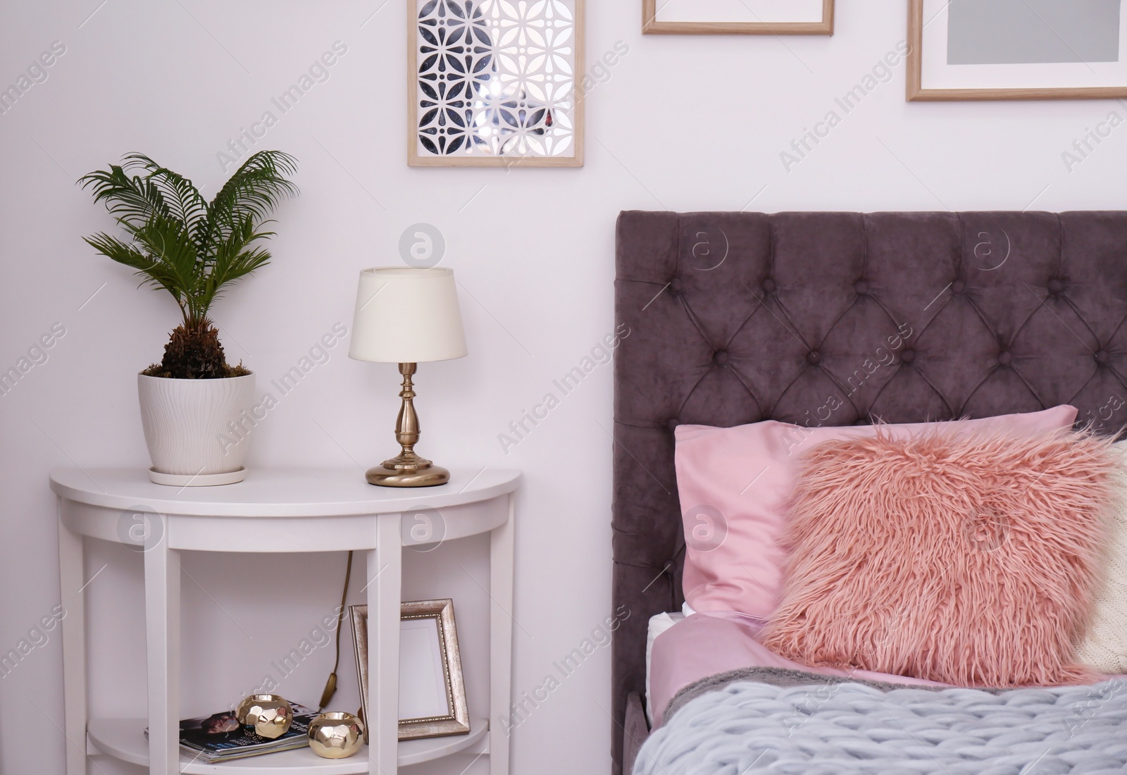 Photo of Comfortable bed and tropical plant with green leaves in room interior