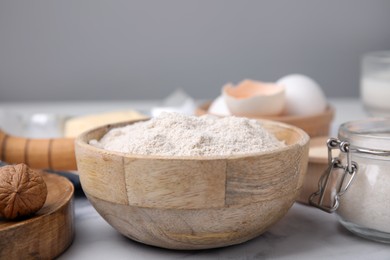 Bowl of flour and other ingredients on white table, closeup