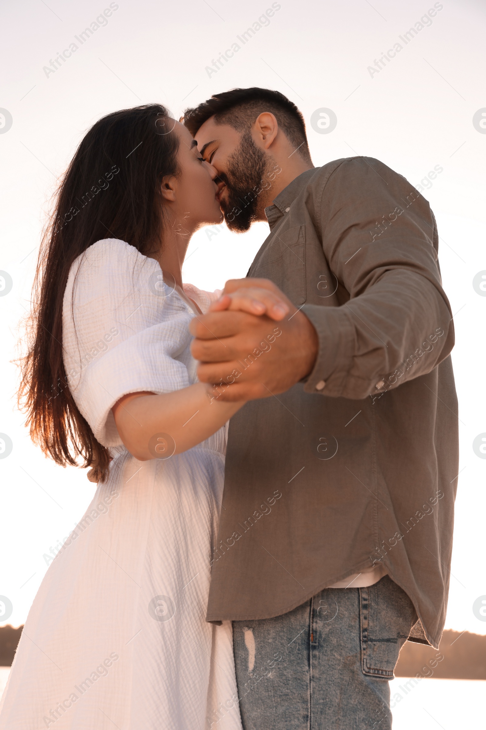 Photo of Beautiful couple dancing and kissing outdoors, low angle view