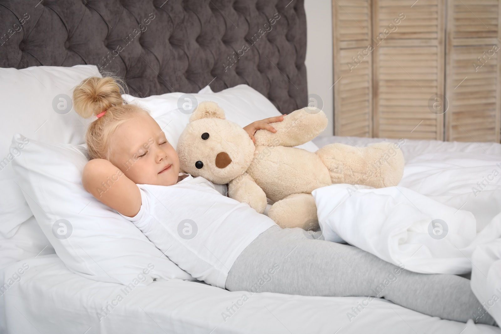 Photo of Cute little girl with teddy bear sleeping in bed
