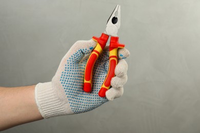 Photo of Man with combination pliers on grey background, closeup