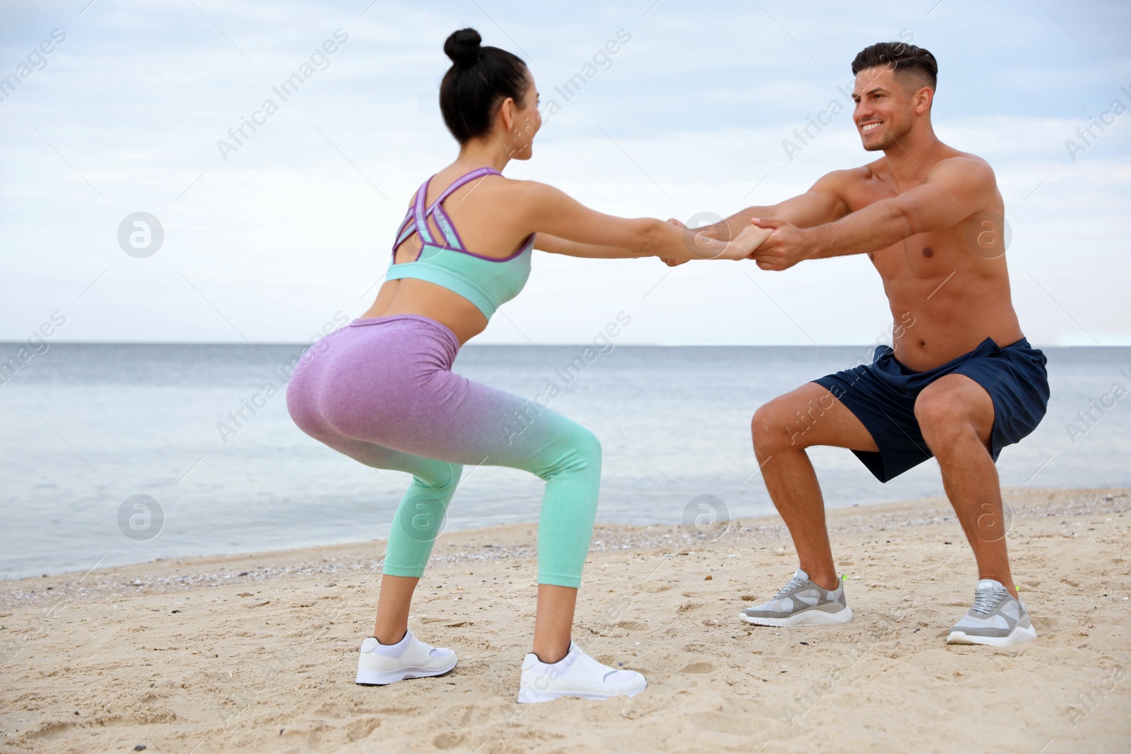 Photo of Couple doing exercise together on beach. Body training