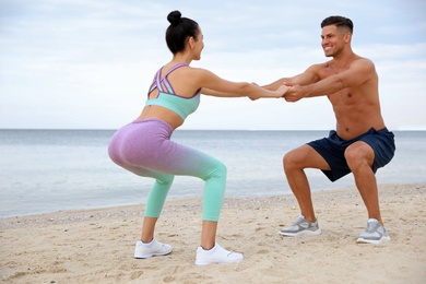 Couple doing exercise together on beach. Body training