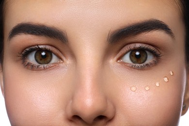 Photo of Closeup view of young woman with gel on skin under eye against white background