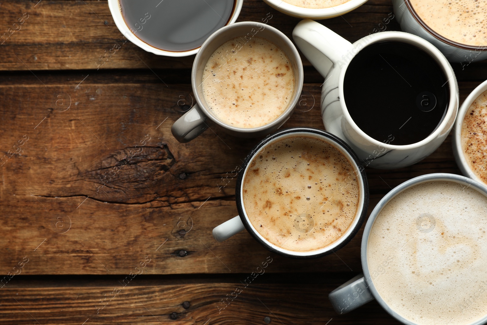 Photo of Many cups of different coffees on wooden table, flat lay. Space for text