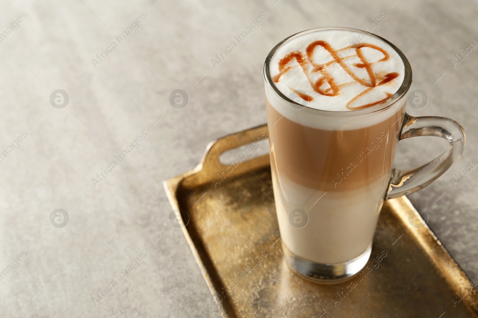 Photo of Tray with glass cup of caramel macchiato on table. Space for text