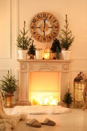 Beautiful room interior with decorative fireplace and potted fir trees. Christmas decor