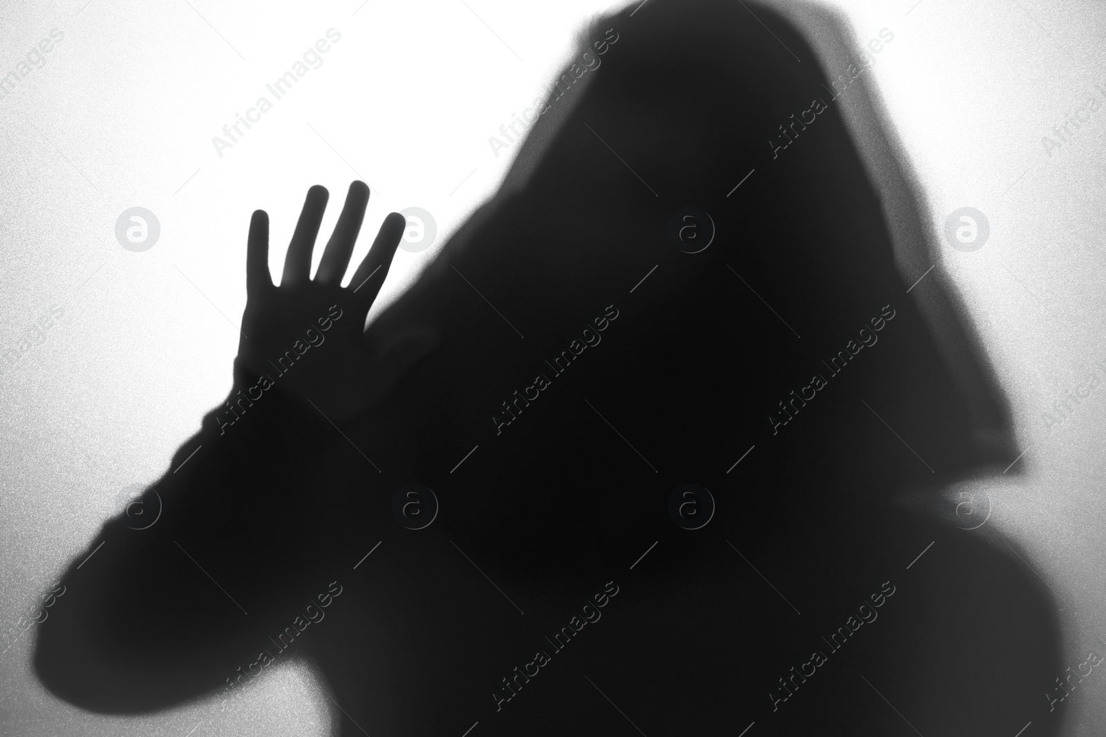 Photo of Silhouette of ghost behind glass against white background