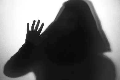 Photo of Silhouette of ghost behind glass against white background