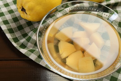Photo of Delicious quince drink in glass bowl and fresh fruit on wooden table, closeup