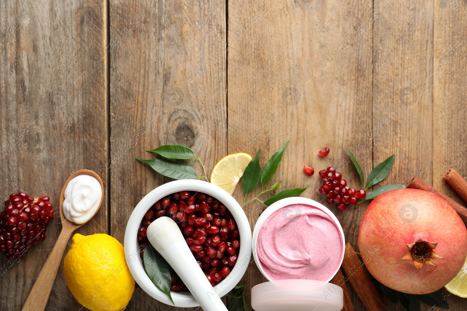 Photo of Flat lay composition with natural homemade mask, pomegranate and ingredients on wooden table. Space for text