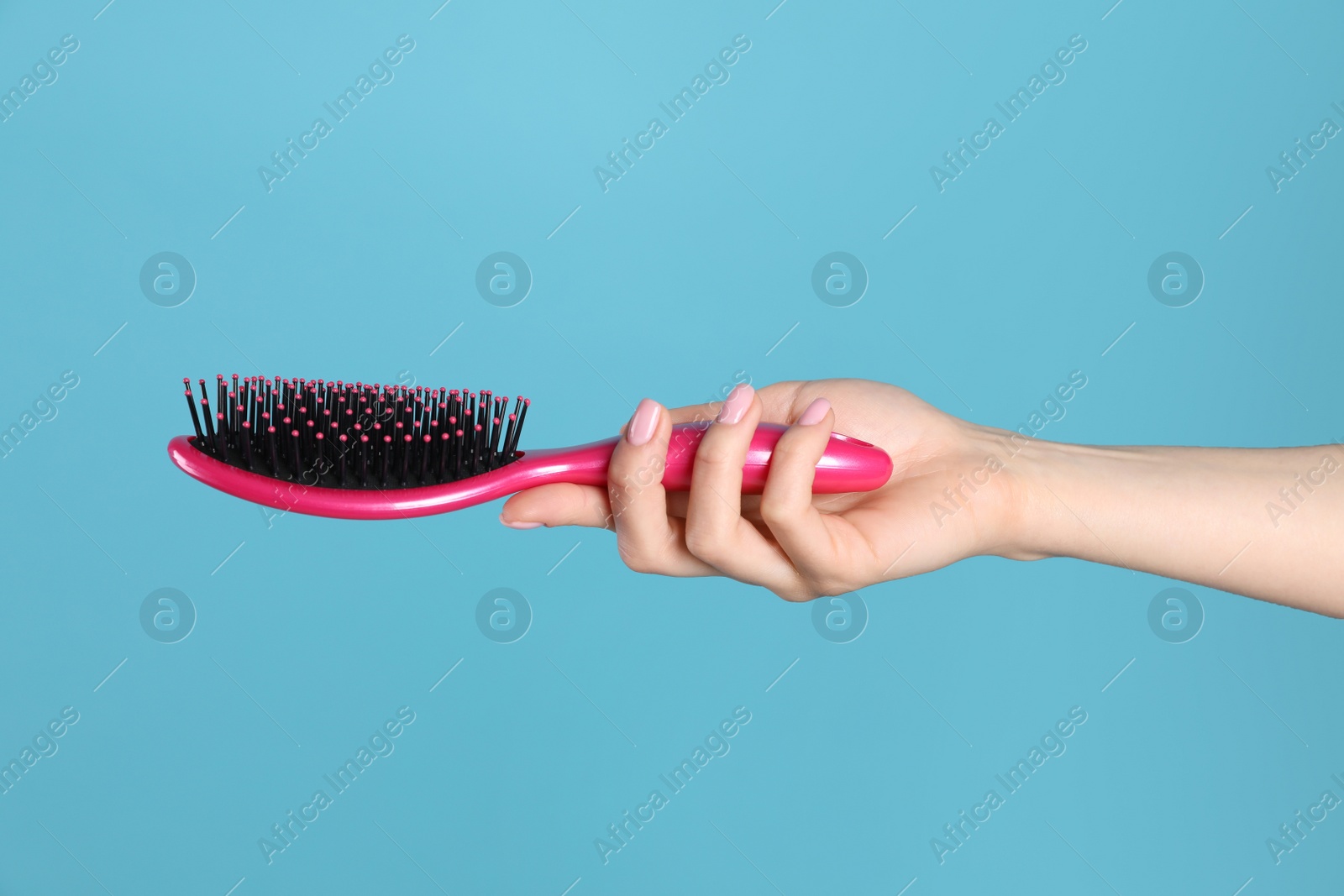 Photo of Woman holding hair brush against blue background, closeup