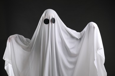 Creepy ghost. Person covered with white sheet on black background