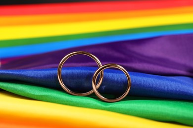 Wedding rings on rainbow LGBT flag, closeup