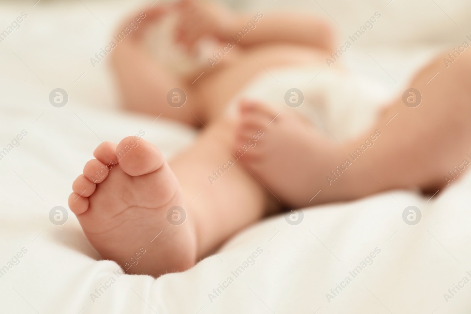 Photo of Cute little baby in diaper on bed, closeup