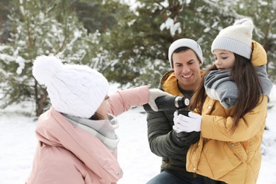 Photo of Happy family with thermos outdoors on winter day. Christmas vacation