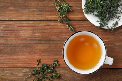 Photo of Aromatic herbal tea with thyme on wooden table, flat lay. Space for text
