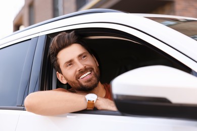 Photo of Happy man looking out of car window, view from outside. Enjoying trip