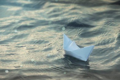 Paper boat floating on water outdoors. Space for text