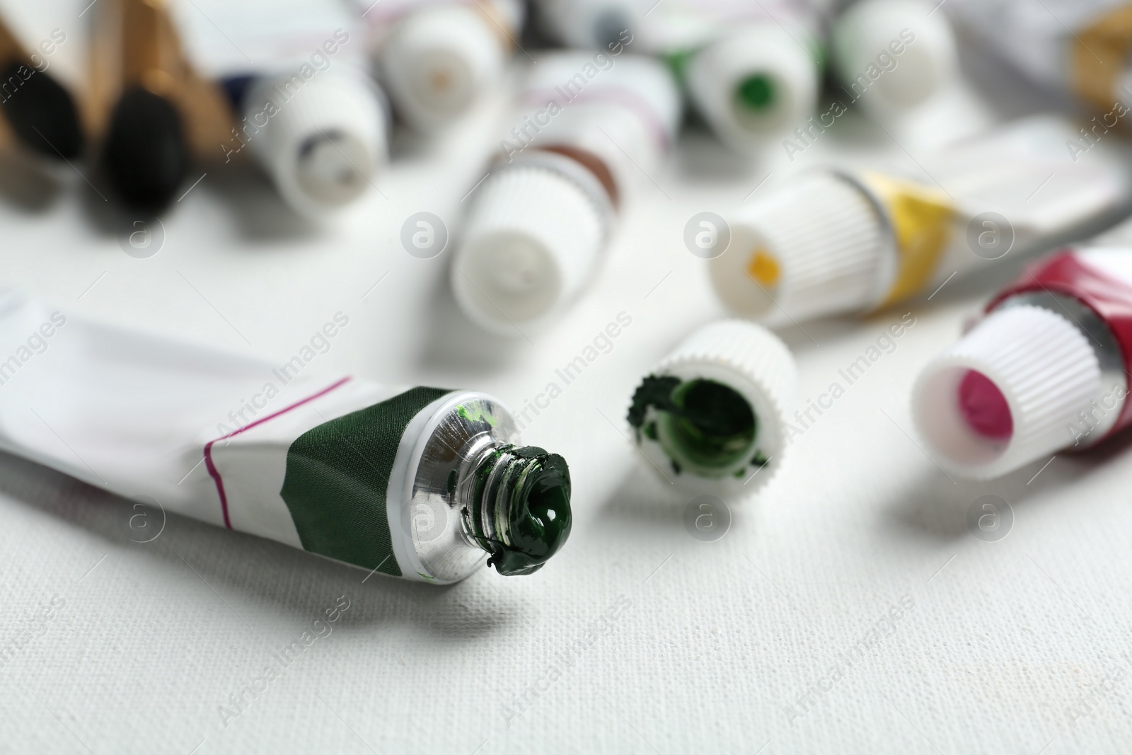 Photo of Tubes with paints on blank canvas, closeup