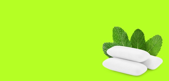 Image of Menthol chewing gum pillows and mint leaves on bright green background, space for text. Banner design