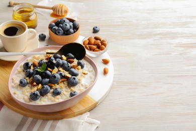 Photo of Healthy oatmeal porridge and ingredients served on wooden table. Space for text