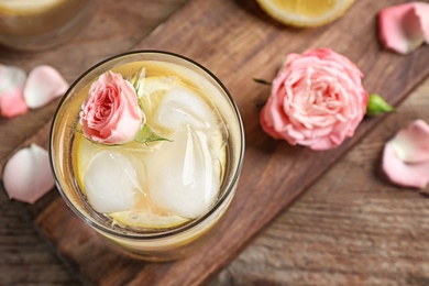 Photo of Delicious refreshing drink with lemon and rose on wooden table, top view