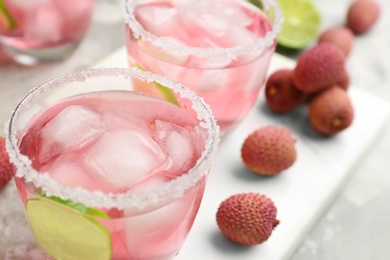 Lychee cocktail with lime and ice on table, closeup