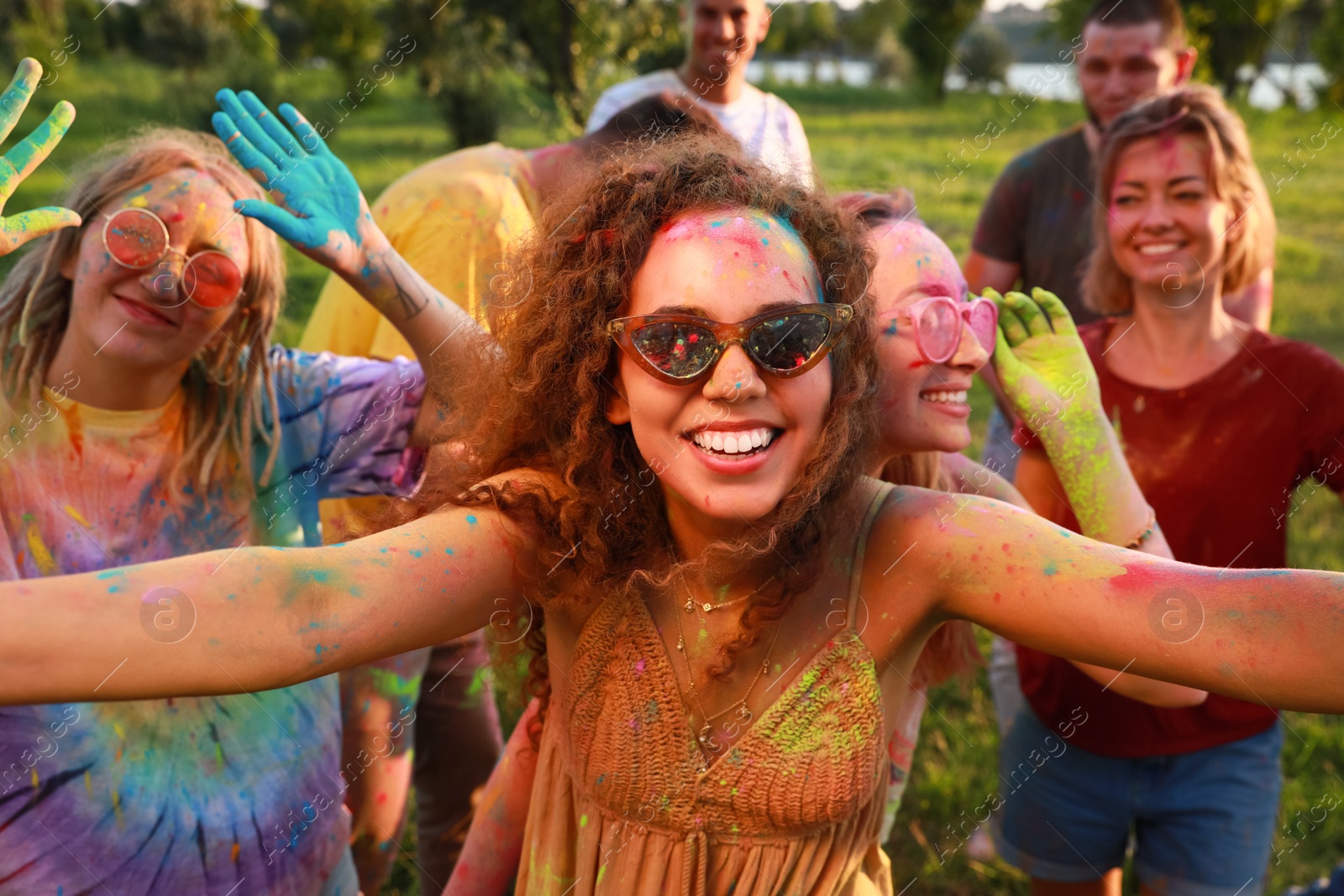 Photo of Happy friends covered with colorful powder dyes outdoors. Holi festival celebration