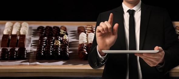 Image of Production line of chocolate candies. Man with tablet, closeup. Banner design