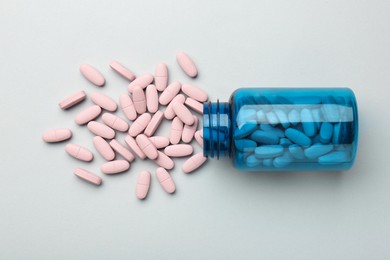 Photo of Vitamin pills and bottle on grey background, top view