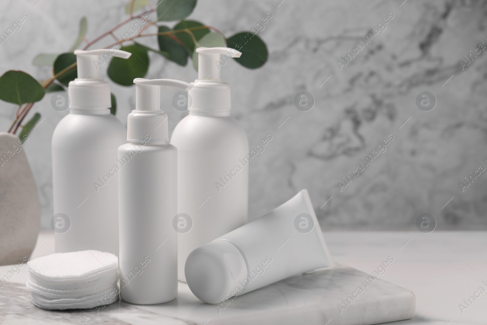 Photo of Different face cleansing products and cotton pads on white table. Space for text