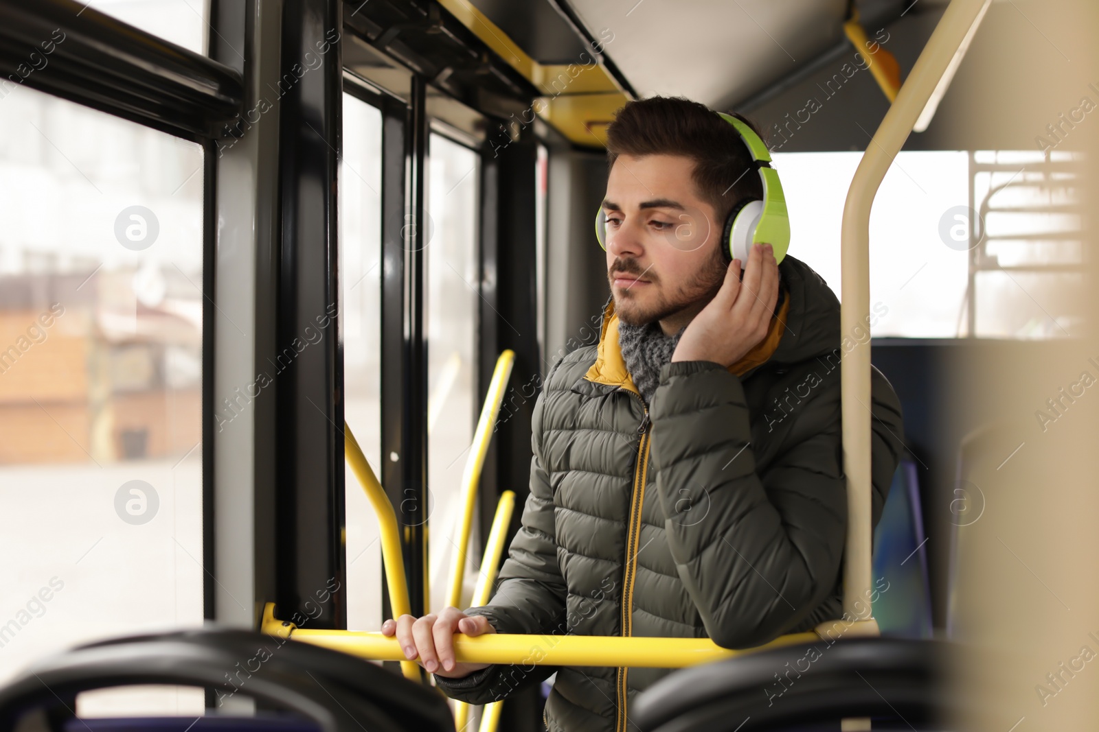 Photo of Young man listening to music with headphones in public transport