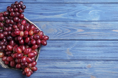 Fresh ripe juicy grapes on blue wooden table, top view. Space for text