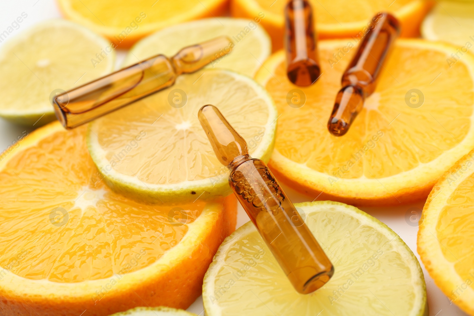 Photo of Skincare ampoules with vitamin C, lemon and orange slices on white background, closeup